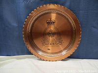 Full view of a round solid copper tray with an engraved Canadian Armed Forces Europe emblem, scalloped edge, and hammered texture around rim.