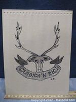Photo of first artwork showing black and white line drawing of Cudich & Rich cap badge featuring a stag skull with antlers and banner with text 'CUDICH N RICH'. Signed 'L.D.'.