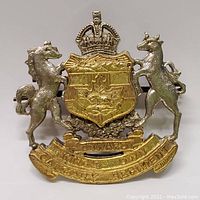 Full view of the bi-metal cap badge showing the animals, crown, shield with beaver and maple leaf, motto, and regiment name.