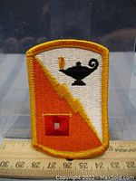 Close-up image of the military patch showing detailed embroidery, colors, and symbols with a clear ruler underneath for scale.