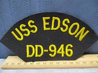 Front side of the USS Edson DD-946 patch with yellow embroidery on black fabric, ruler for size reference.