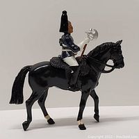 View of vintage British soldier mounted on black horse figurine, showing profile and details of soldier and horse tack.