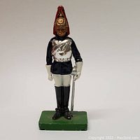 Front view of vintage British soldier figurine in ceremonial uniform showing painted details and green base