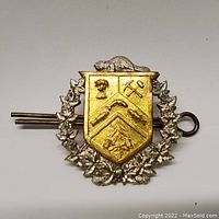 Front view of the WW2 Canadian bi-metal cap badge showing the gold and silver color details and regiment symbols including beaver, mining tools, rifles, and maple leaves.