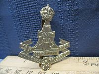 Close-up photo of Yorkshire Regiment cap badge, showing crown at the top and central cross with inscriptions.