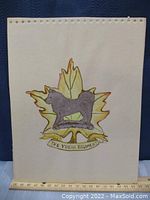 Full view of one artwork on white paper with perforated top edge, showing the Yukon Regiment cap badge design with colored dog and maple leaf, with measuring scale beneath.