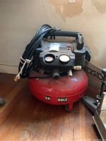 Full view of the red and black Porter Cable air compressor showing the tank, handle, and attached hose coiled on top.