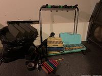 Overview photo showing the guitar rack, accordion, xylophones, and accessories on carpeted floor.