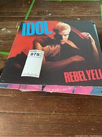 Billy Idol Rebel Yell vinyl album on wooden floor with partial pink album edge visible