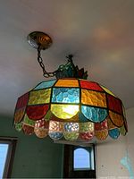 Full view of the multicolor stained glass hanging light fixture installed on ceiling, showing chain suspension and colorful glass panels.