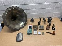 Overview of assorted vintage items including gramophone horn, clock, pipe, figurines, and boxes.