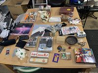 View of assorted lot items on table including Dragonball VHS tapes, eyeglass cases, ceramic pitcher, and small collectibles.
