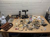 Overview of large assortment of jewelry on table showing variety of bracelets, earrings, rings, necklaces, brooches, mostly in silver and gold tones.
