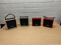 Front view of 4 vintage 8 track players, two beige and two red, placed on floor against wall