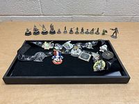 Photo of a black tray holding Disney Star Wars metal tokens positioned in the back row and various pins in front with Star Wars and Mickey Mouse themes.