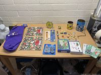 Photo showing all items in the Looney Tunes lot arranged on table including clock, mugs, assorted figurines, pins, calendars, ornaments, and bag.