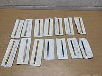 Top-down photo showing all 13 Mary Kay pencils unopened and laid out on a flat surface, visible in blister packaging attached to their backing cards.