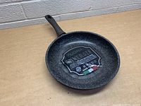 Fudina 12 inch stoneware frying pan front view showing speckled black interior and handle.