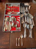 Photo showing full assortment of forks, knives, spoons, and specialty pieces on table and in felt-lined case.