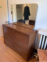 Front and side view of wood dresser with nine drawers and large rectangular mirror attached at back.