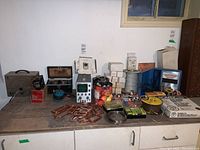 Photo of entire workbench with electrical instruments and supplies including multimeter, signal generator, wires, boxes, copper connectors, and more.