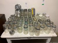 Wide view of all mason jars on table showing quantity and assortment of sizes and lids.