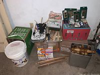 Wide view of lot with painting supplies, electrical parts, and plumbing fittings packed in boxes and containers