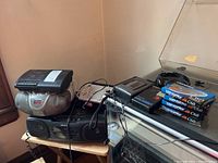 Photo showing multiple portable electronic devices stacked on and around a small wooden table, including Sony cassette players, Electrohome CD player, various cassette tapes and accessories.