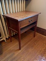 Side view of the wooden side table showing tapered legs and drawer handle.