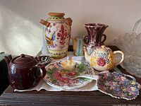 Wide view showing Sadler brown teapot, floral embossed teapot, decorative urn, vases, plates, and glass bowl.