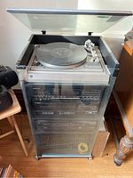 Full view of stereo system including turntable, receiver, tape deck, CD player and cabinet with dust cover open.