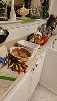 Photo showing the ceramic peppers on rope, hand painted serving bowl, Pyrex loaf pan, copper molds, several teapots, and other ceramic items arranged on kitchen countertop