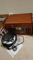 Full view of Crosley CR74 wood finish radio unit and Jensen portable CD player placed on floor with manuals visible.