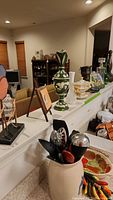 Photo showing green ornate pitcher, Asian motif gravy tureen, milk glass bud vase, glass decanters