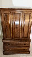 Front view of the entire wooden Ethan Allen armoire, showing the closed doors and bottom drawers.