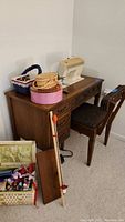 Full view of vintage Singer Futura 900 sewing machine in wooden cabinet with matching chair, sewing baskets and supplies arranged on and beside the cabinet.
