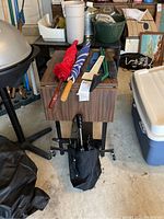 Full view of the typewriter table with fold-down sides and three umbrellas placed on top, showing umbrellas with wooden handles and fabric canopies.