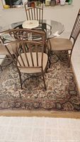 Glass-top round table with four chairs positioned on the area rug, showing the overall rug design and scale relative to furniture.