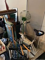 Black Rubbermaid yard tool holder standing holding multiple yard tools with wooden handles and metal heads, surrounded by additional garden and yard tools in a garage setting.