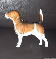 Photo of Beswick hound dog figurine showing side profile with brown and white glaze on a dark background.