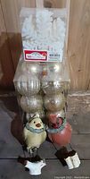 Photo showing packaged white snowflake decorations on top, transparent container holding silver and gold Christmas balls in the middle, and 2 vintage style hanging bird ornaments on bottom.