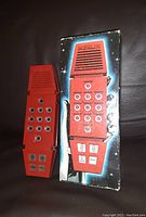 Red Merlin handheld electronic game with a numeric and function button layout on a space-themed backing card.