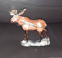 Side view of closed moose figurine trinket holder showing detailed painting and realistic sculpting on a base.