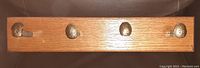 Front view of the wooden rack with four metal railroad spikes functioning as hooks, wood grain visible.