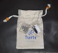 Photo showing Turix fabric pouch with drawstring and wooden beads, silver-tone chain, and amethyst pendant wrapped in plastic.