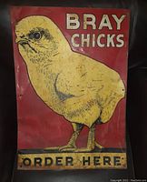 Photo of vintage metal sign with a yellow chick on red background and text 'BRAY CHICKS ORDER HERE'. Shows wear and scratches.