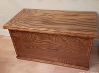 Front angle of wooden rectangular blanket box with natural wood grain finish.
