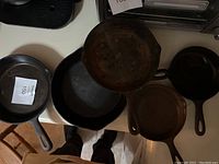 Five cast iron skillets on a counter, showing overall condition and different sizes.