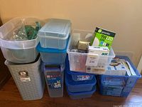 Grouped assorted plastic containers and bins stacked with several boxes of lightbulbs and accessories packed inside.