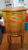 Front view of standing wooden jewelry chest with five drawers and two side doors